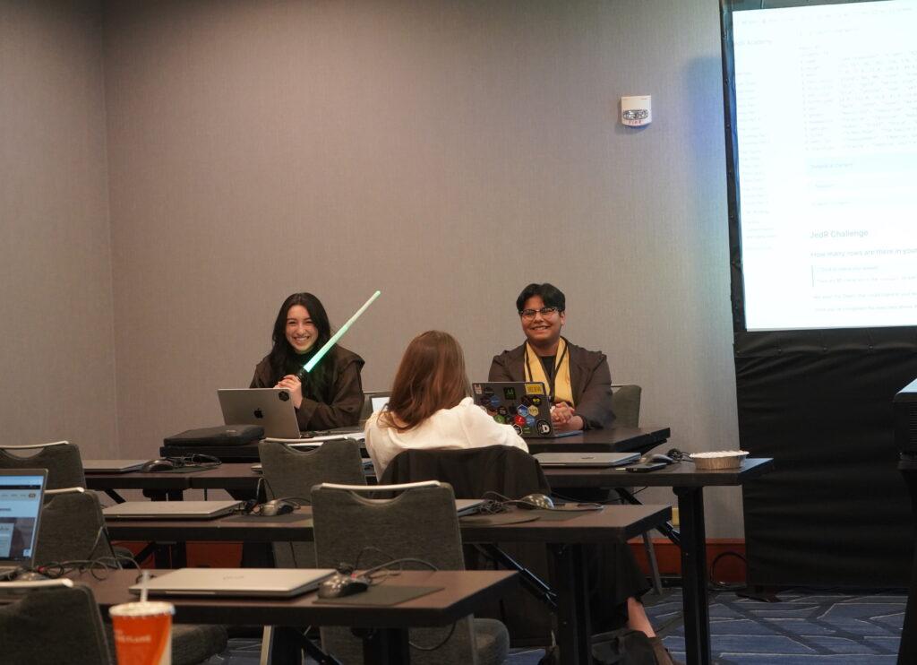 Two speakers teaching, dressed in Star Wars theme and holding a lightsaber.