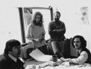 A black and white photo of journalists surrounding a table covered with investigative research papers.