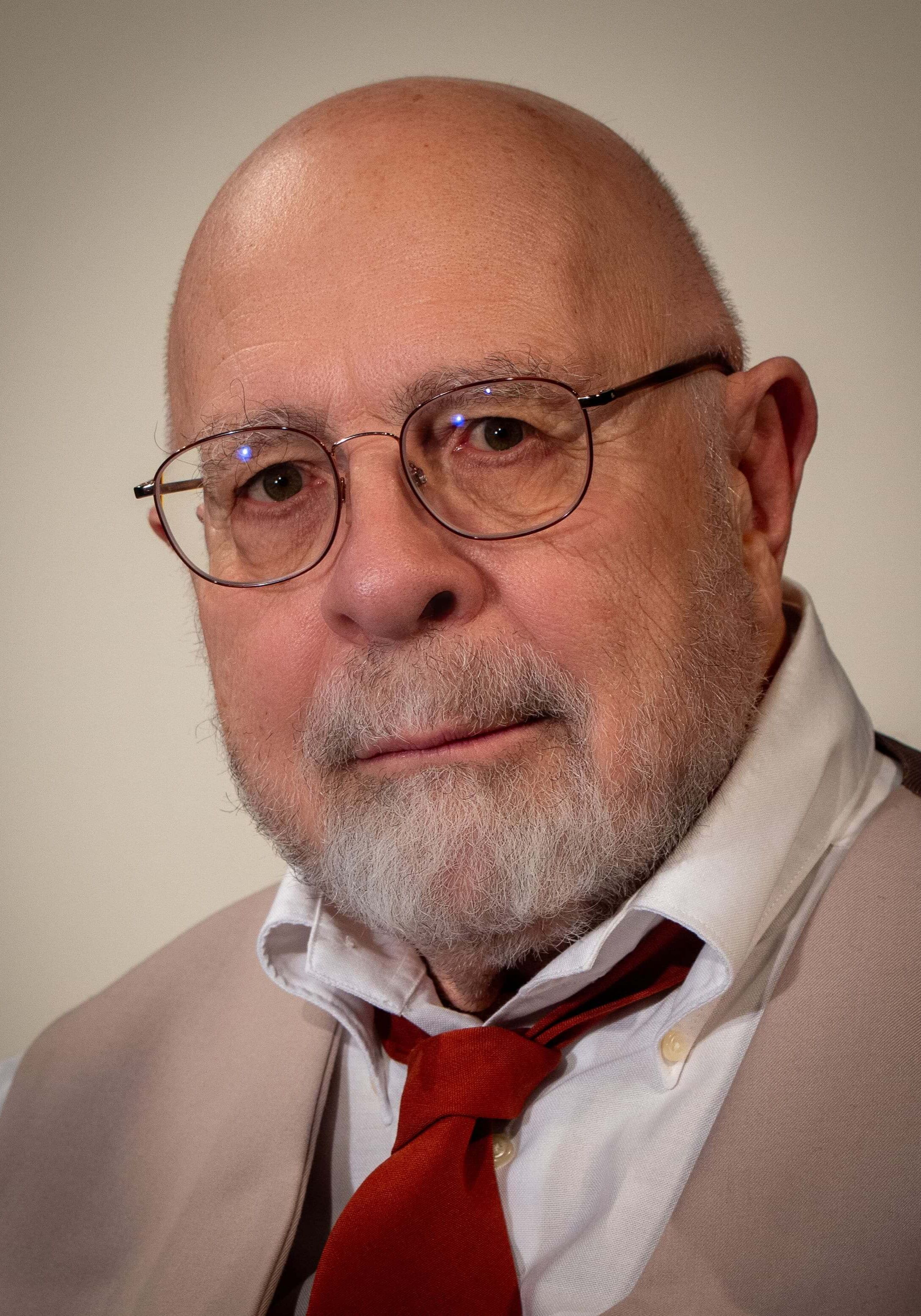 Portrait of Hank Newer. Hank is wearing a tan suit and a red tie.